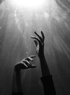 two hands reaching up into the air above water