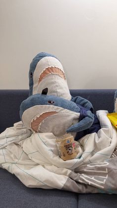 a stuffed shark laying on top of a blue couch next to a yellow banana peel