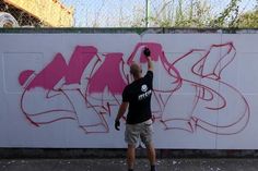 a man standing in front of a wall with graffiti on it, taking a photo