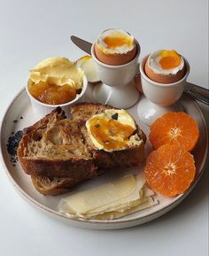 a plate with bread, eggs and oranges on it