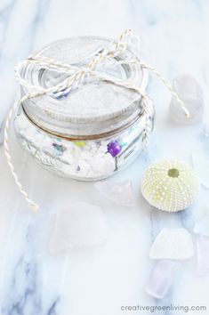 some glass jars and sea urns on a marble table with white flowers in them