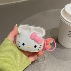 a hello kitty cell phone case is held by a woman's hand next to a coffee cup