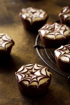 chocolate cupcakes with white frosting and spider web decoration on top, sitting on a cooling rack