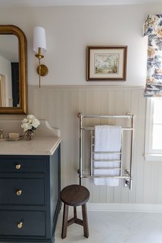 a bathroom with a sink, mirror and towel rack on the wall next to it