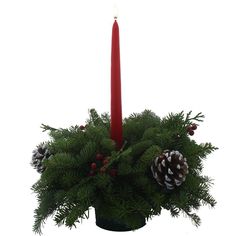 a red candle sitting on top of a green vase filled with pine cones and greenery