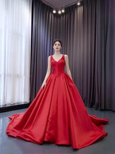 a woman in a red ball gown standing next to a window with curtains behind her