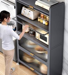 a woman standing in front of a gray cabinet with lots of food on top of it