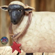 a statue of a sheep with a red star on it's neck sitting on a wooden table