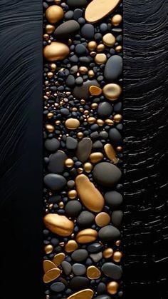 a black and gold wall with some rocks on the bottom, and two different colors