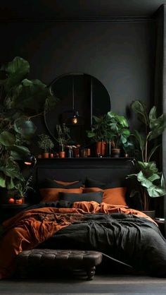 a bedroom with black walls and plants in pots on the headboard, an orange comforter