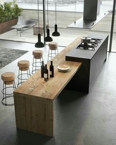 a modern kitchen with an island counter and stools in front of the stove top