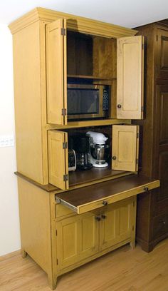 a kitchen cabinet with a microwave on top and cupboards behind it in a room that has wood floors