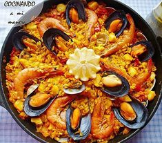 a pan filled with seafood and rice on top of a table