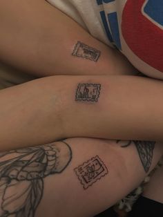 two people with tattoos on their legs sitting next to each other and one is holding the other's leg