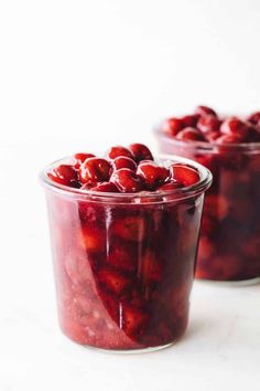 cranberry sauce in a glass jar on a white surface with two bowls full of it