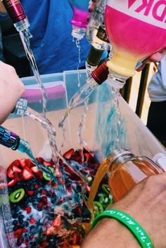 someone is pouring wine into a bucket filled with fruit