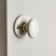 a white door handle with gold knobs on the side of a wooden door,