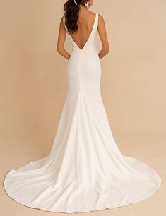 the back of a woman in a white wedding dress with her hands on her hips