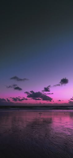 an airplane is flying in the sky at sunset with clouds reflected in the wet sand