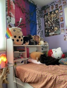 a cat laying on top of a bed next to a shelf filled with stuffed animals