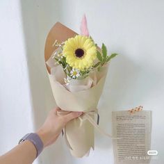 a person holding a bouquet of flowers next to an open book