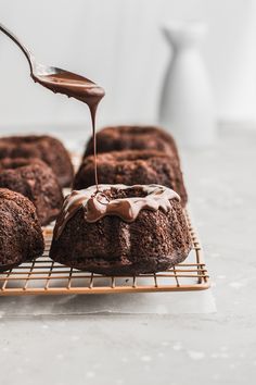 chocolate bundt cake being drizzled with icing on a cooling rack