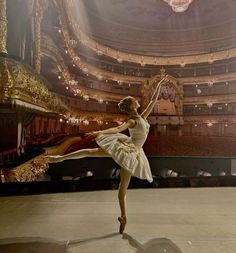 a ballerina in a white dress is performing on stage with an ornate chandelier