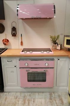 a pink stove top oven sitting inside of a kitchen next to a wooden countertop