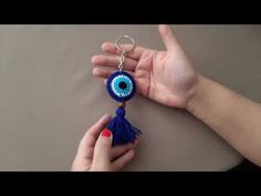 a person is holding a key chain with an evil eye on it and a blue tassel