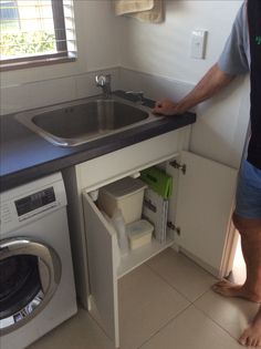 a man standing in front of a sink next to a washer and dryer