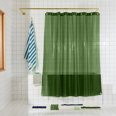 a green shower curtain in a white tiled bathroom