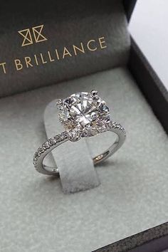 an engagement ring in a box with diamonds on the band and side stones around it