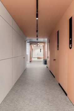 an empty hallway with pink walls and black door handles on either side of the doors