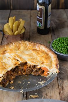 there is a pie with meat and peas on the table next to other food items