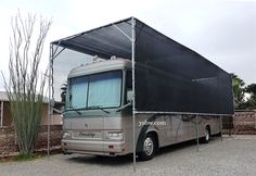 a silver bus parked in front of a brick building with a black awning over it