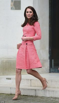 a woman in a red and white dress is walking down the street with her hand on her hip