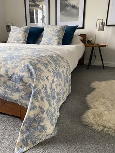 a bed with blue and white comforter in a bedroom next to pictures on the wall