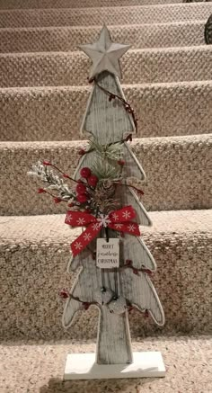 a wooden christmas tree sitting on top of a set of stairs