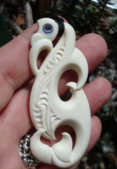 a hand holding a white brooch with an evil eye on it's side