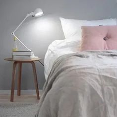 a bedroom with a bed, nightstand and lamp on the side table in front of it