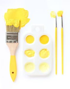 the paintbrush is next to an egg tray with four eggs in it and three other paints