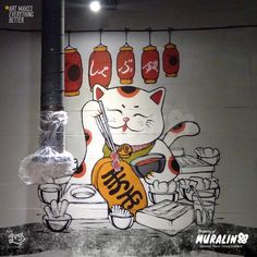 a cat sitting on top of a counter next to a wall with chinese writing and pictures