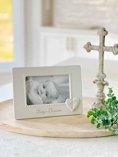 a small white cross with a baby's photo on it and a plant next to it