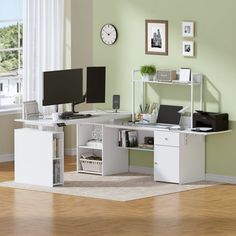 a white computer desk with two monitors and a keyboard on it in front of a window