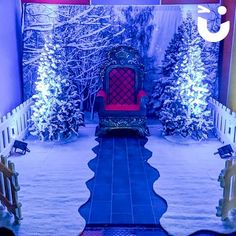 a red chair sitting in the middle of a room filled with snow covered trees and bushes