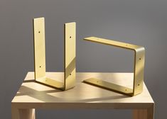 two metal brackets sitting on top of a wooden table