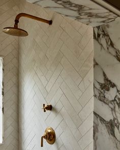 a shower head and hand shower in a bathroom with white marble tiles on the walls