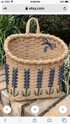 a wicker basket with blue flowers on the side and an iron bow at the top