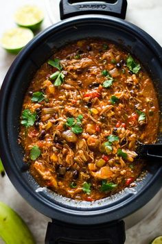 a black pot filled with mexican chicken and tortilla soup next to limes