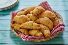 a basket filled with croissants sitting on top of a blue wooden table